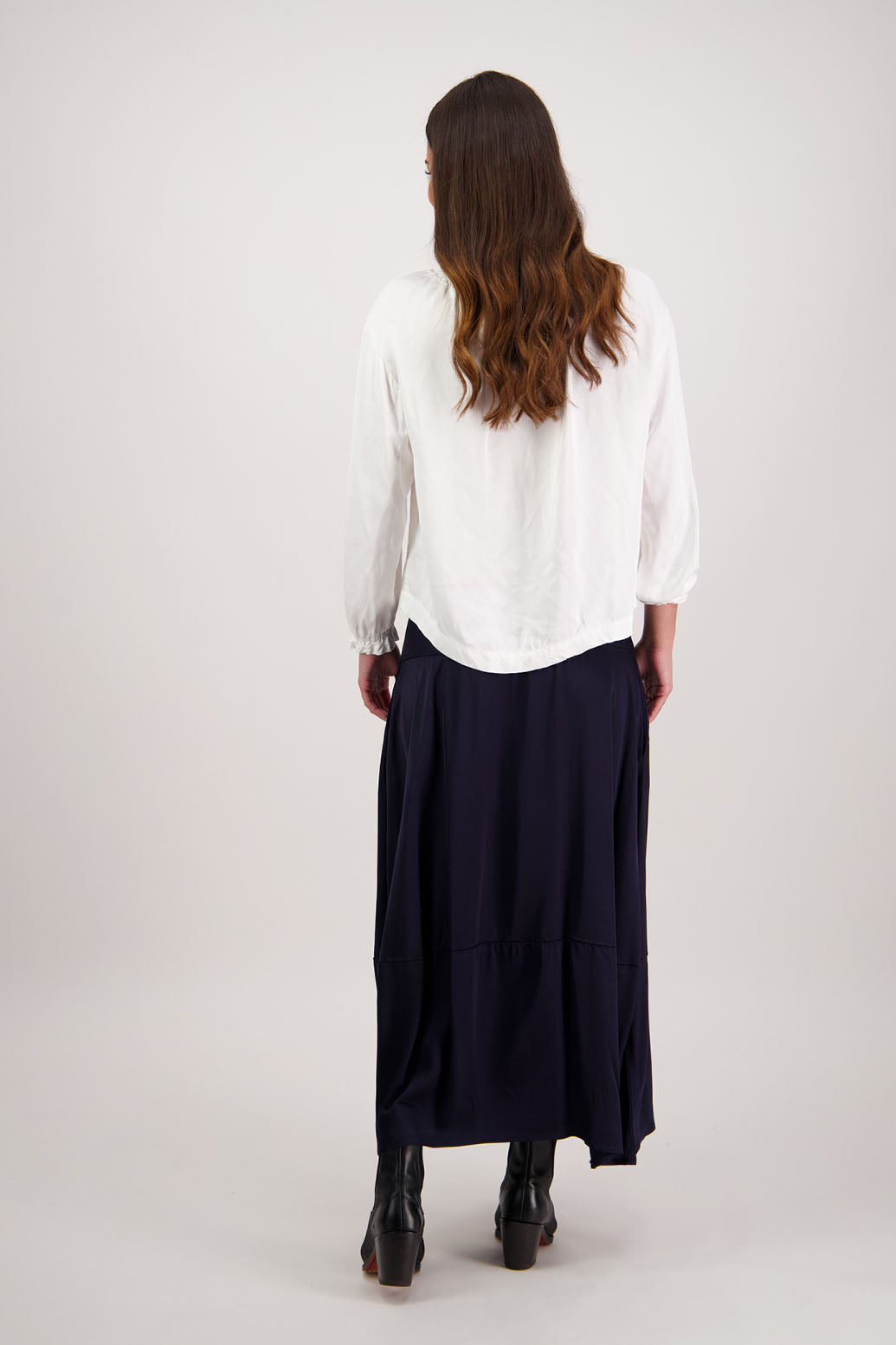 Person wearing a white blouse and navy skirt on a plain background