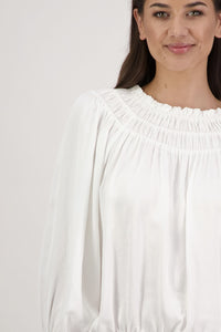 Woman wearing a white blouse against a plain background