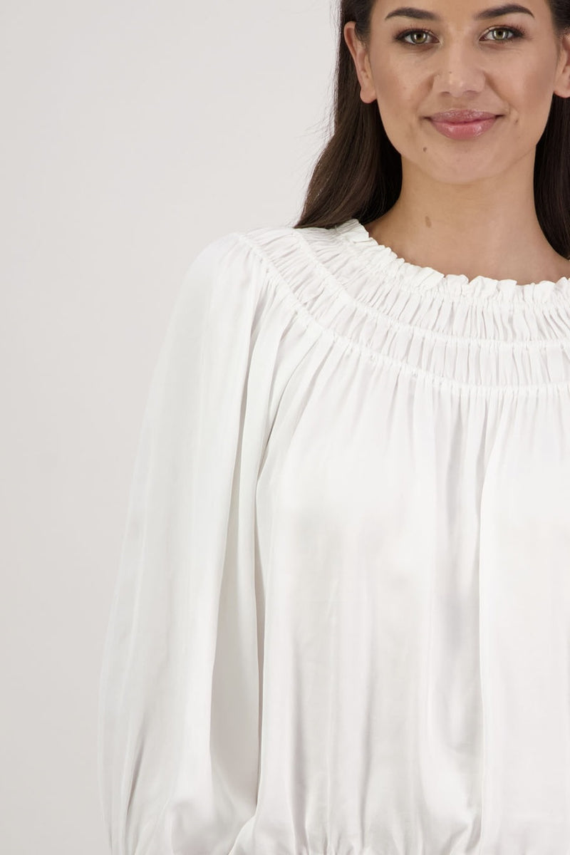 Woman wearing a white blouse against a plain background